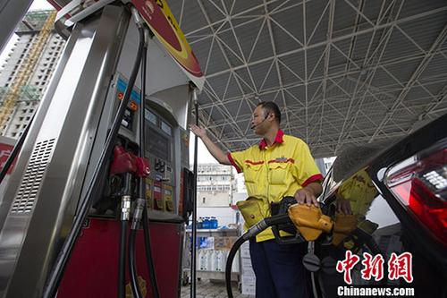 資料圖：一加油站工作人員給車輛加油。中新社記者張?jiān)茢z